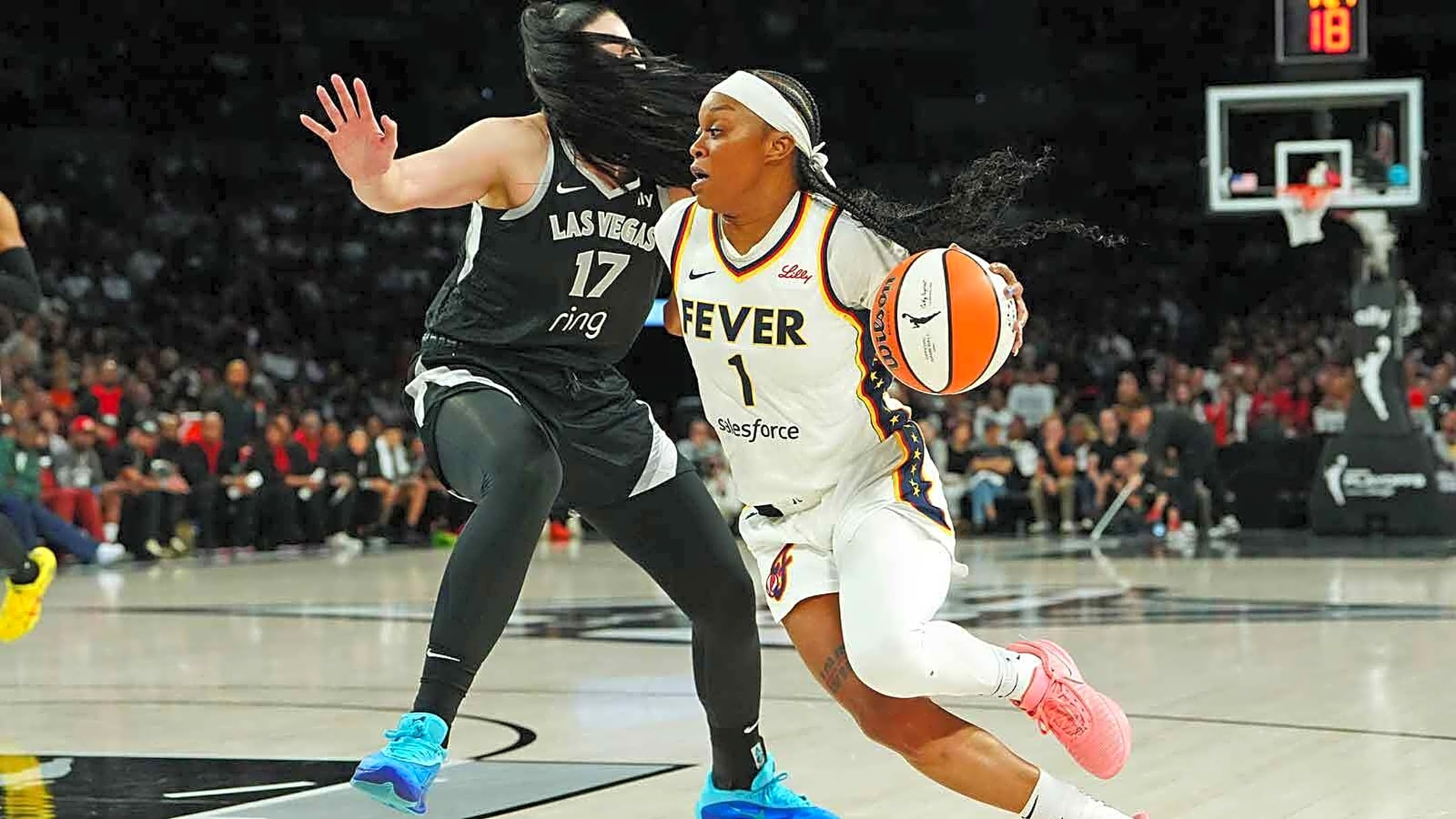 Fever player in white jersey number 1 dribbles with the ball, guarded by a Las Vegas player in black number 17.
