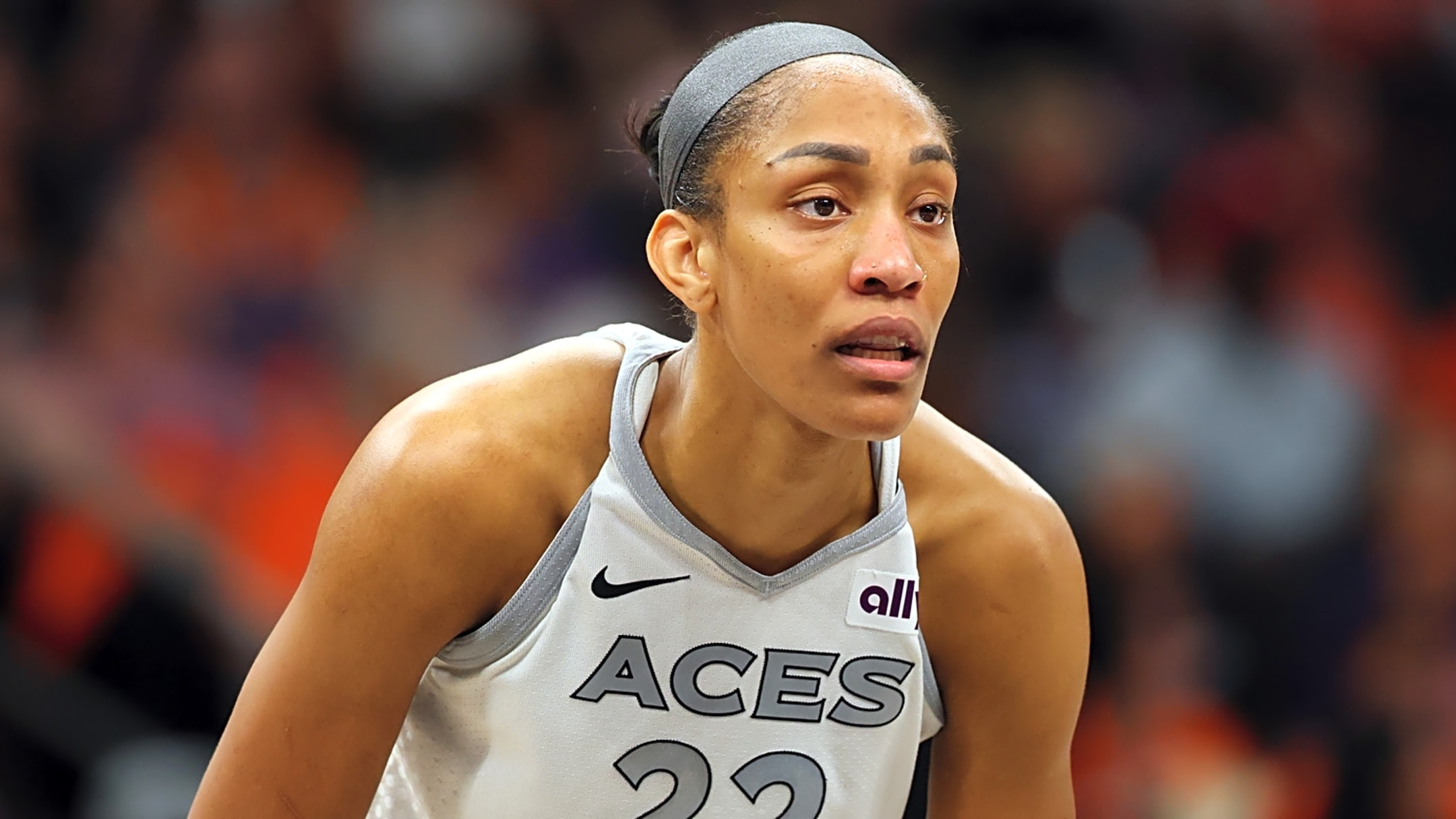 Female basketball player wearing a gray ACES jersey and headband, focused on the game.